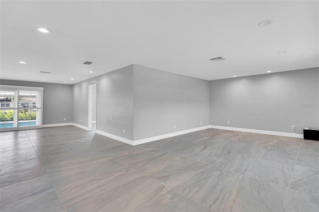 An empty room with gray walls, large-format tile flooring, and a sliding glass door — 3944 DORAL DRIVE, TAMPA, FL