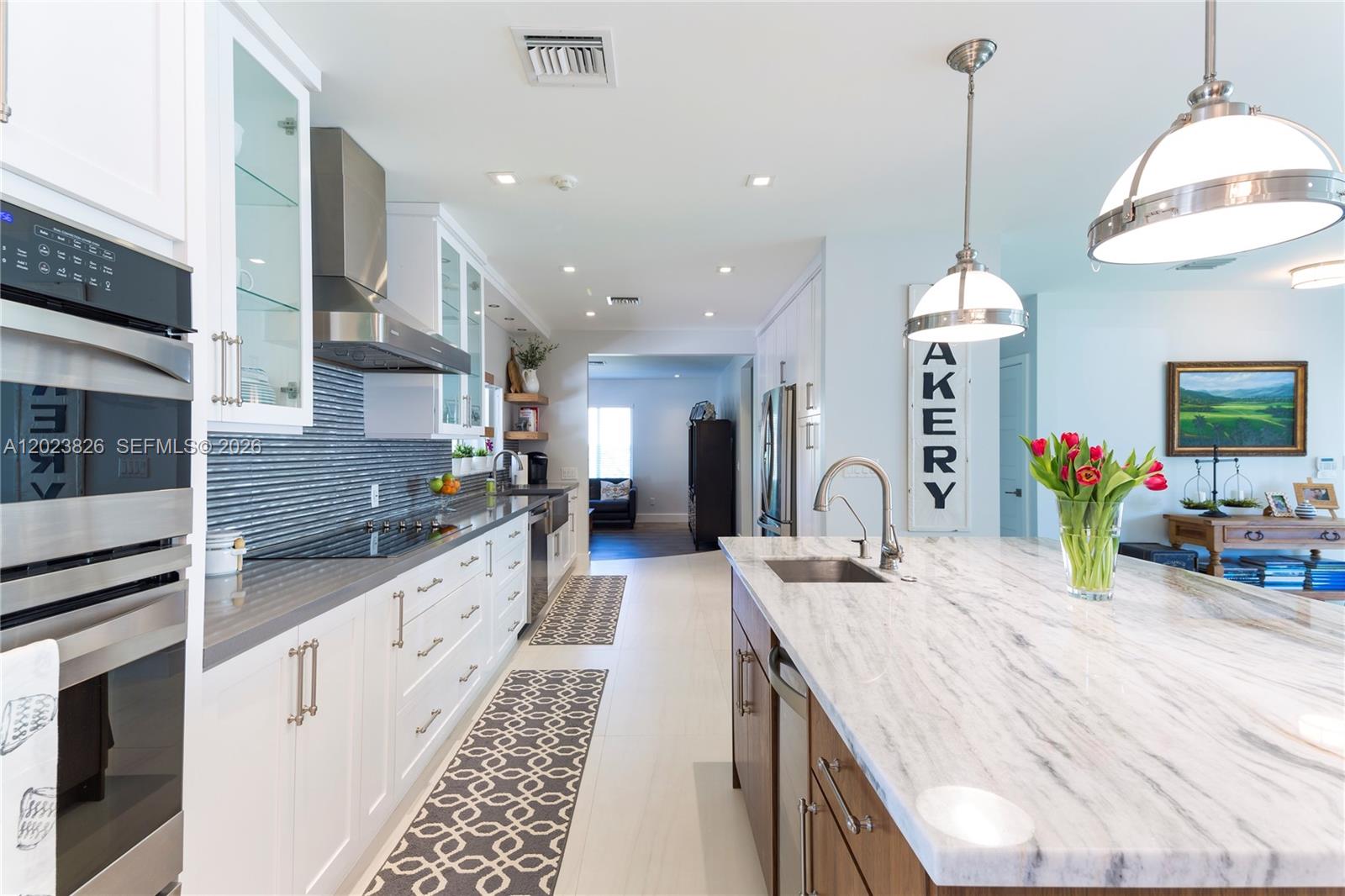 A modern kitchen features white cabinetry, a marble island, and stainless steel appliances — 7980 SW 108th St, Miami FL 33156, MIAMI, FL