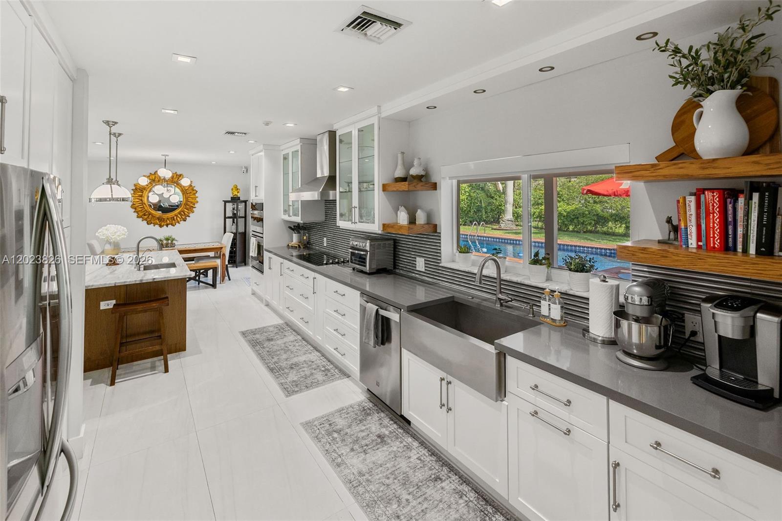 A modern kitchen features white cabinets, gray countertops, a farmhouse sink, and a view of a pool — 7980 SW 108th St, Miami FL 33156, MIAMI, FL