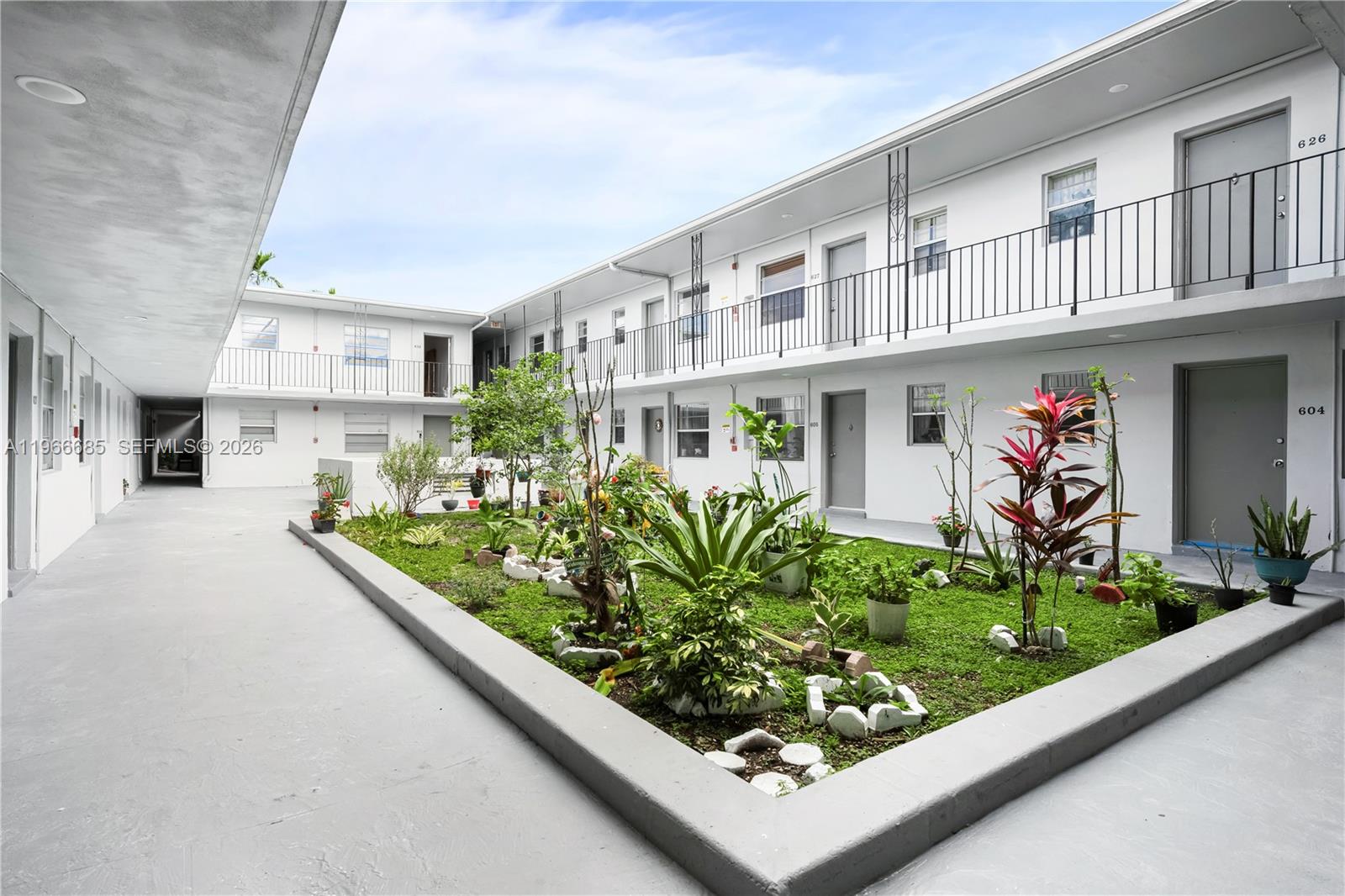 An outdoor courtyard features a central garden bed surrounded by a two-story apartment building — 10375-35-55 SW 40th St # 0, Miami FL 33165, MIAMI, FL