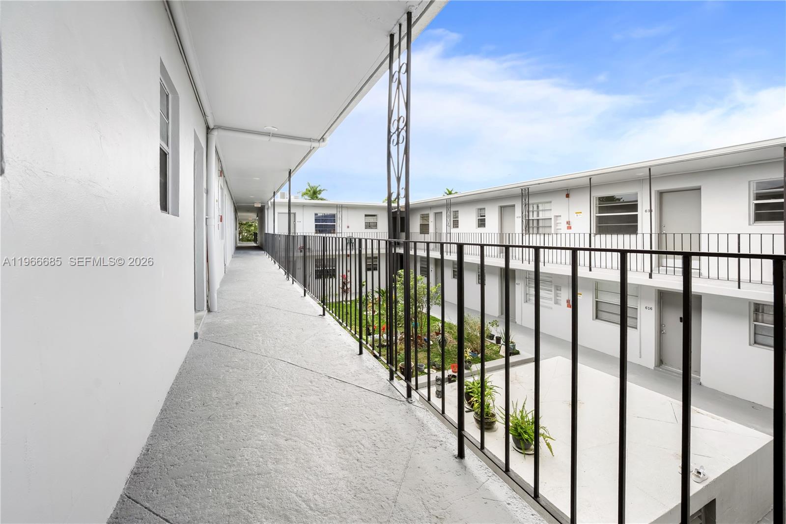 An outdoor walkway overlooks a central courtyard with plants in a multi-story apartment complex — 10375-35-55 SW 40th St # 0, Miami FL 33165, MIAMI, FL