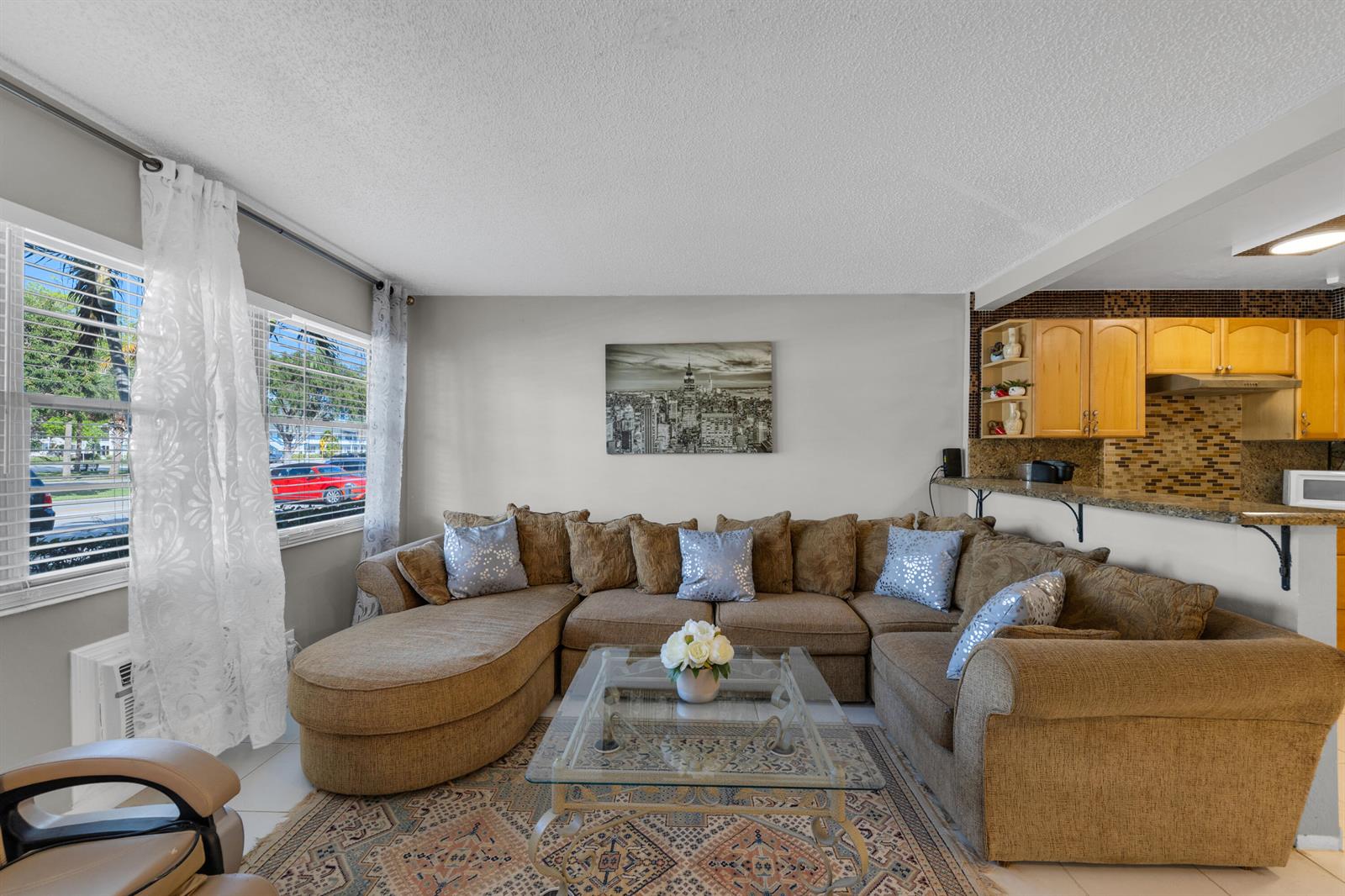 A living room features a large brown sectional sofa, a glass coffee table, and an open kitchen — 5 Newport A, Deerfield Beach FL 33442, DEERFIELD BEACH, FL