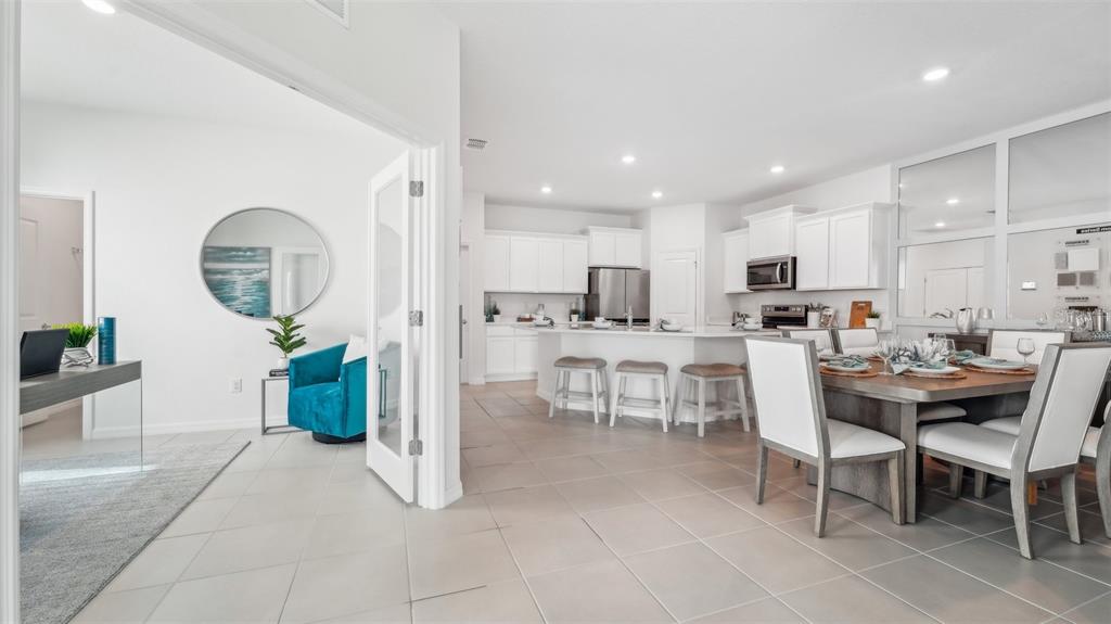 A bright, open-concept kitchen and dining area with white cabinetry and light tile flooring — 32864 RUSTIC RISE ROAD, SAN ANTONIO, FL