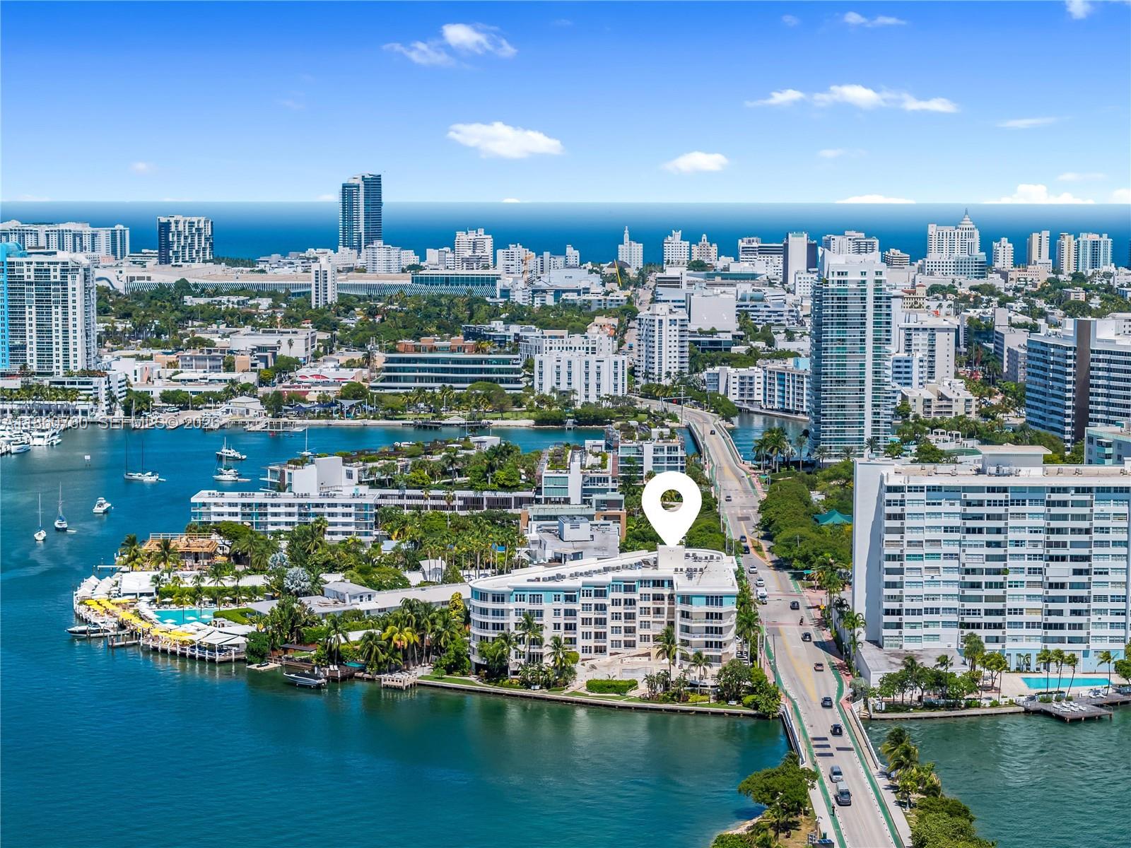 An aerial view of a multi-story waterfront apartment building with a pool and palm trees — 1 Century Ln # 202, Miami Beach FL 33139, MIAMI BEACH, FL