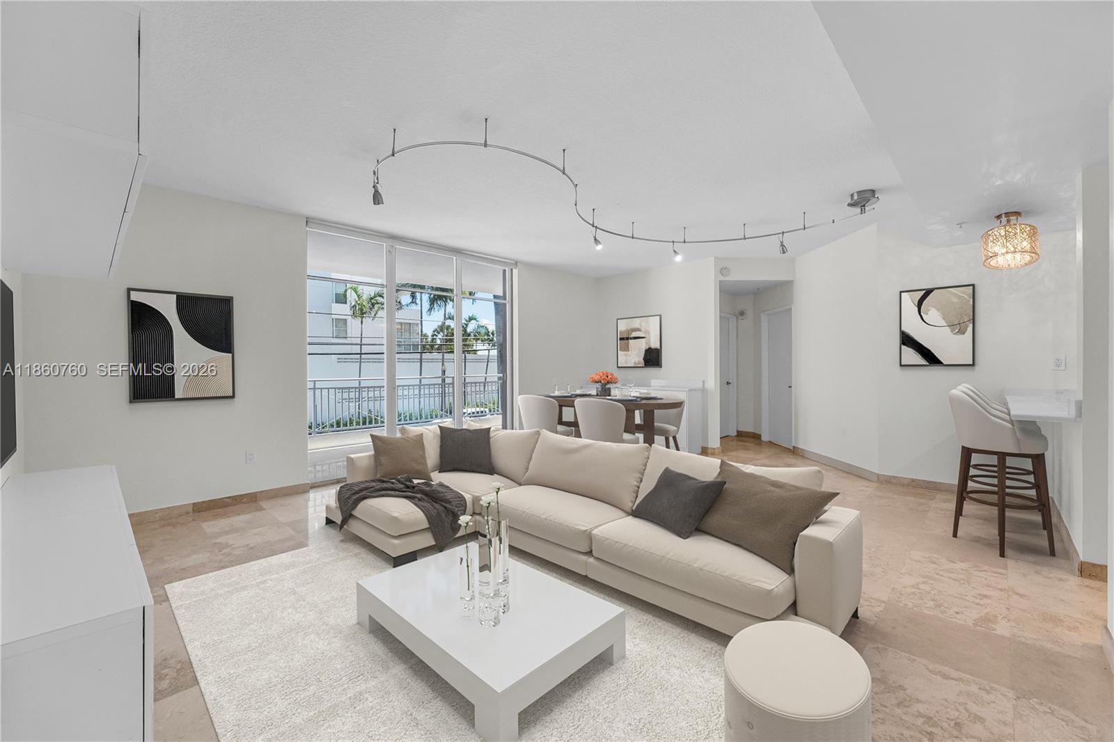 A modern living room features a large sectional sofa, track lighting, and beige tile flooring — 1 Century Ln # 202, Miami Beach FL 33139, MIAMI BEACH, FL
