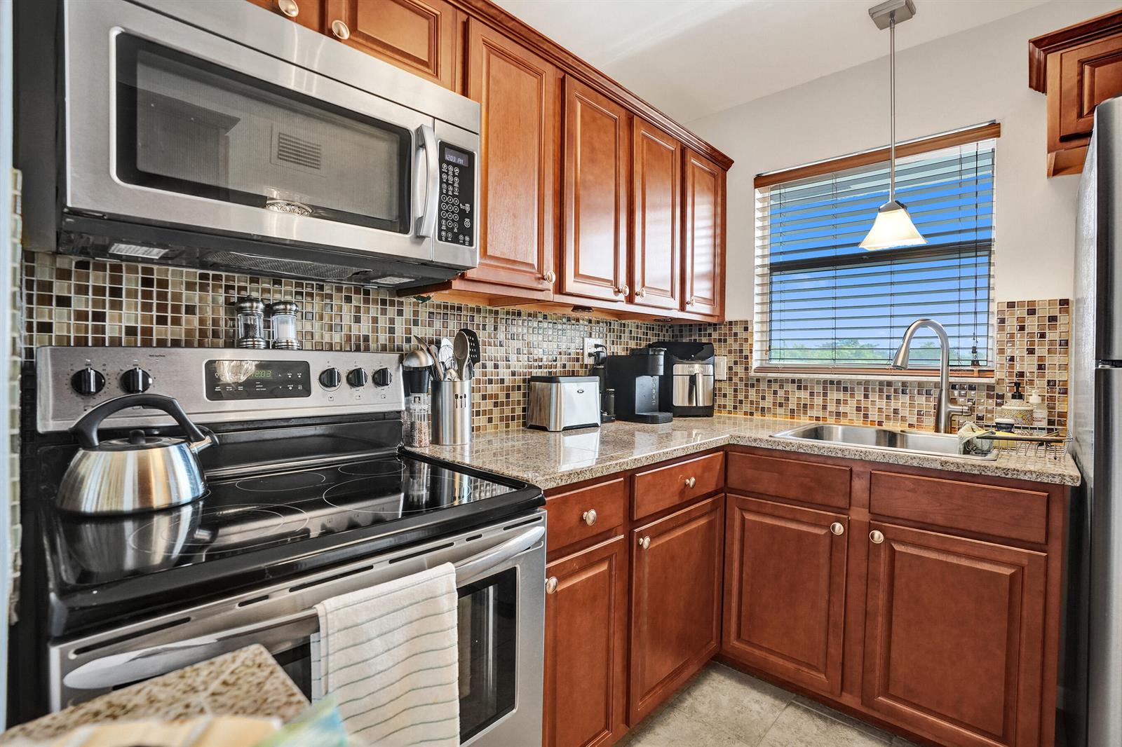 A kitchen with wood cabinets, stainless steel appliances, granite countertops, and a mosaic tile backsplash — 2901 E Sunrise Lakes Drive E # 305, Sunrise FL 33322, SUNRISE, FL