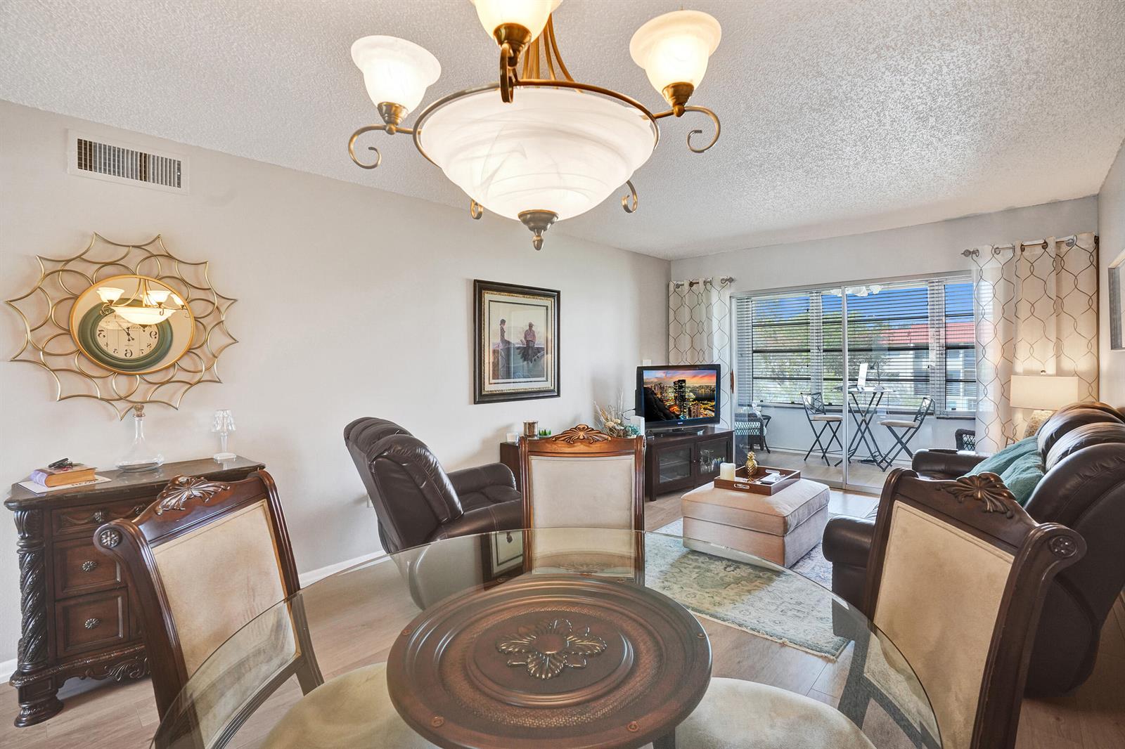 A dining area with a glass table and chairs opens into a living room — 2901 E Sunrise Lakes Drive E # 305, Sunrise FL 33322, SUNRISE, FL