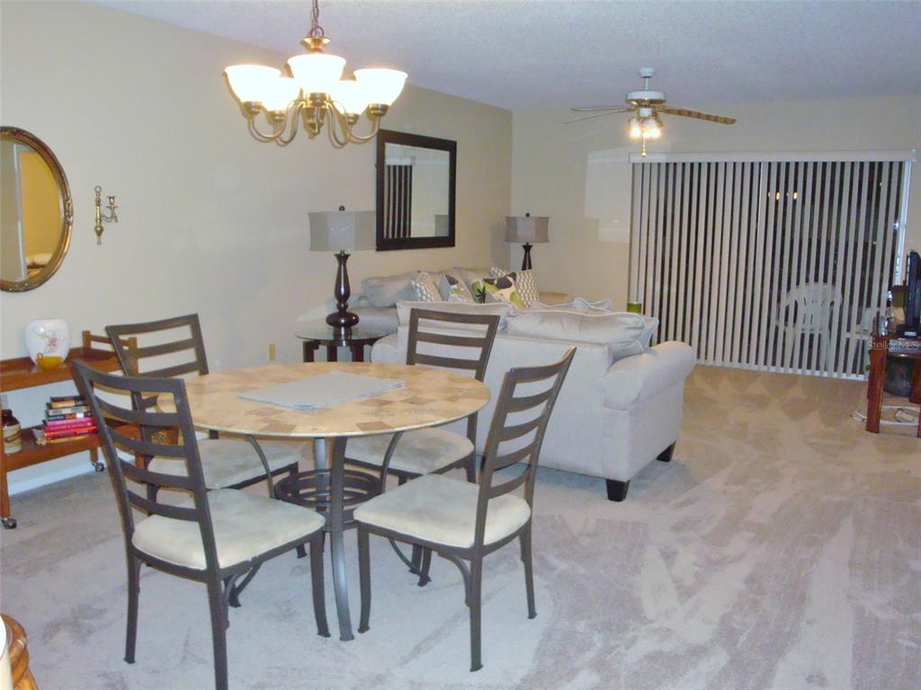 A dining area with a round table and chairs sits in front of a living room — 244 CYPRESS LANE UNIT 244, OLDSMAR, FL