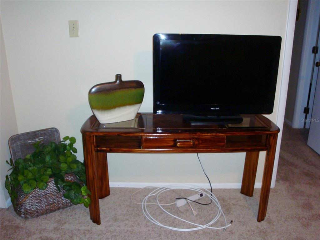 A Philips television and a decorative vase sit on a wooden console table — 244 CYPRESS LANE UNIT 244, OLDSMAR, FL