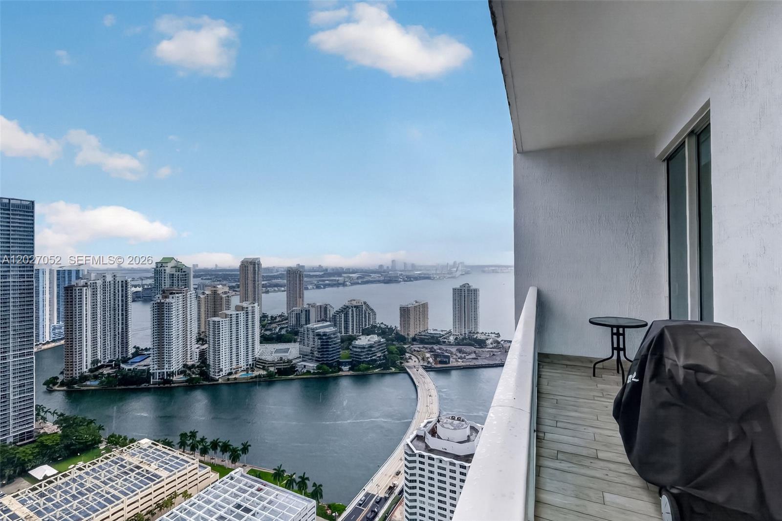 A living room features a white sofa, a wooden coffee table, and floor-to-ceiling windows — 950 Brickell Bay Dr # 4504, Miami FL 33131, MIAMI, FL