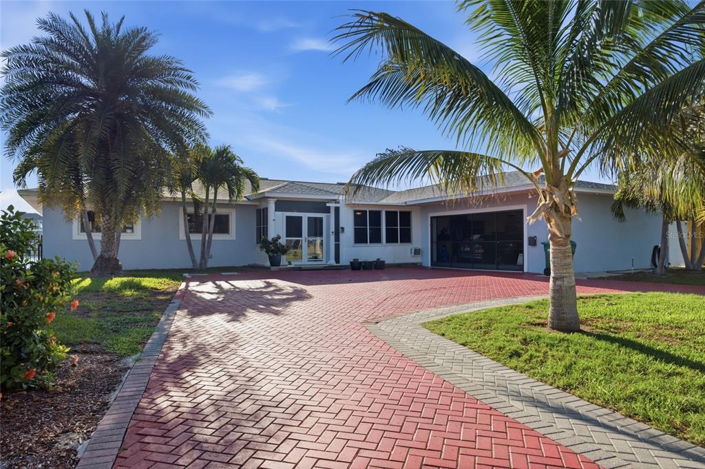A single-story house with a red brick driveway, palm trees, and a garage — 1818 DOLPHIN BOULEVARD S, ST PETERSBURG, FL