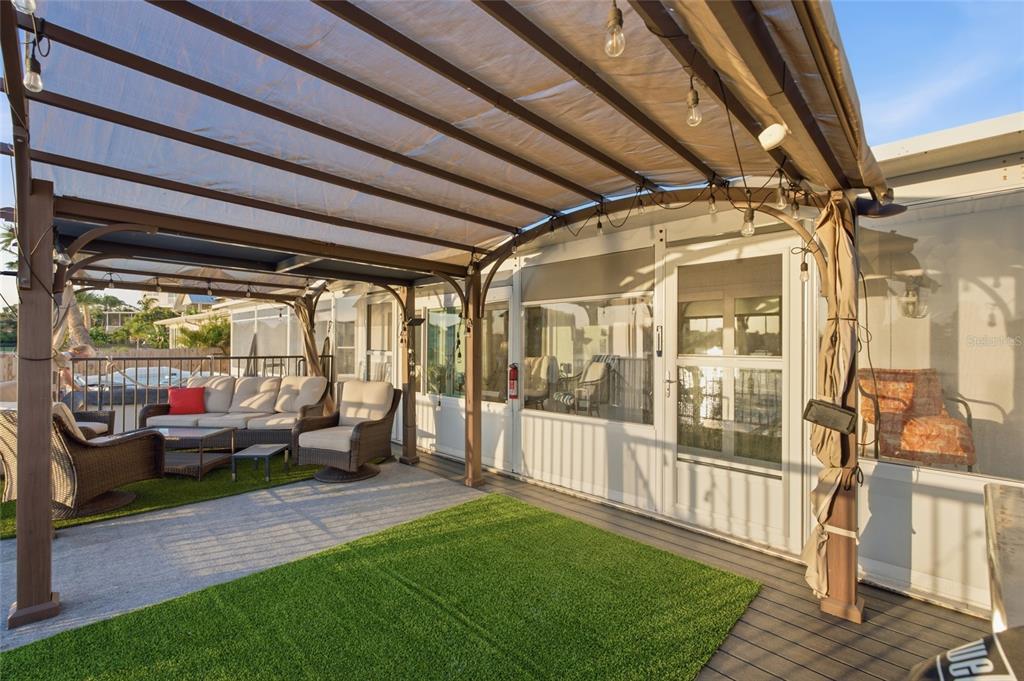 A covered outdoor patio features artificial turf, wicker furniture, and string lights — 1818 DOLPHIN BOULEVARD S, ST PETERSBURG, FL