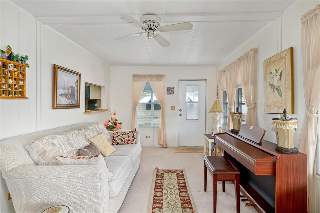 A living room features a white sofa, a piano, and a ceiling fan — 5619 BAYSHORE ROAD UNIT 423, PALMETTO, FL