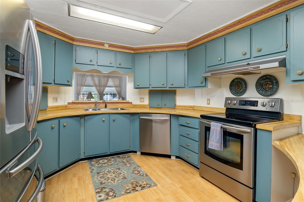 A kitchen with blue cabinets, wood countertops, and stainless steel appliances — 5619 BAYSHORE ROAD UNIT 423, PALMETTO, FL