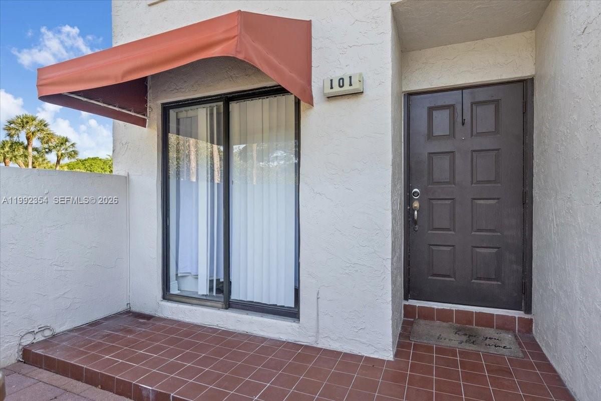 The exterior of a unit features a brown door, a sliding glass door, and tile flooring — 101 Lincoln Ct # 101, Deerfield Beach FL 33442, DEERFIELD BEACH, FL