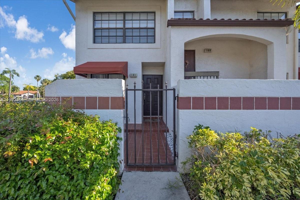 The exterior of a two-story residential building features a gated entrance to unit 101 — 101 Lincoln Ct # 101, Deerfield Beach FL 33442, DEERFIELD BEACH, FL