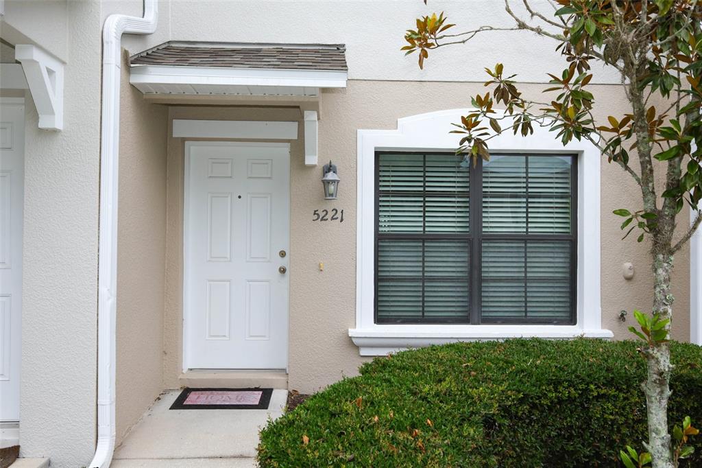 A white front door with a small awning and a window with blinds — 5221 WINDSOR LAKE CIRCLE, SANFORD, FL