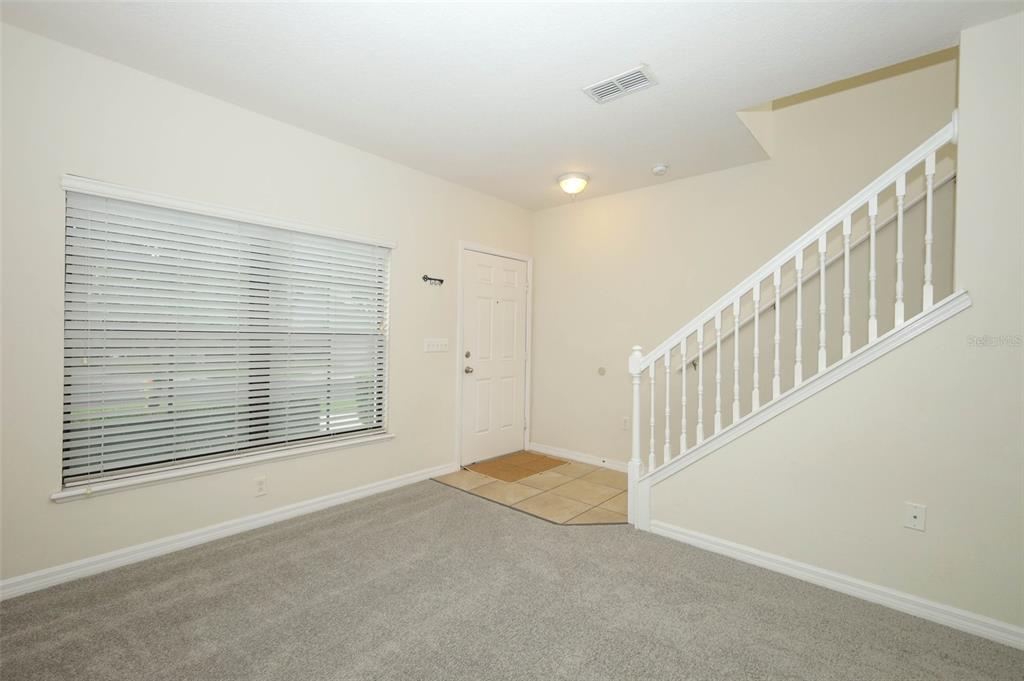 An entryway with carpeted flooring, a large window, a front door, and a staircase — 5221 WINDSOR LAKE CIRCLE, SANFORD, FL