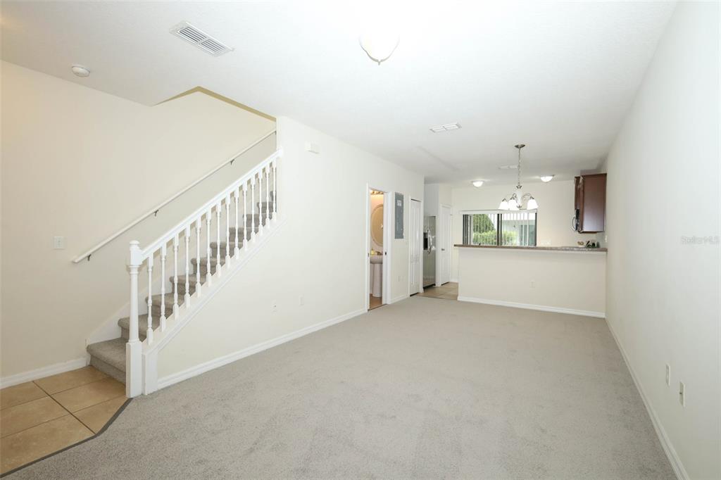 An interior view shows a carpeted living area with a staircase and an open kitchen — 5221 WINDSOR LAKE CIRCLE, SANFORD, FL