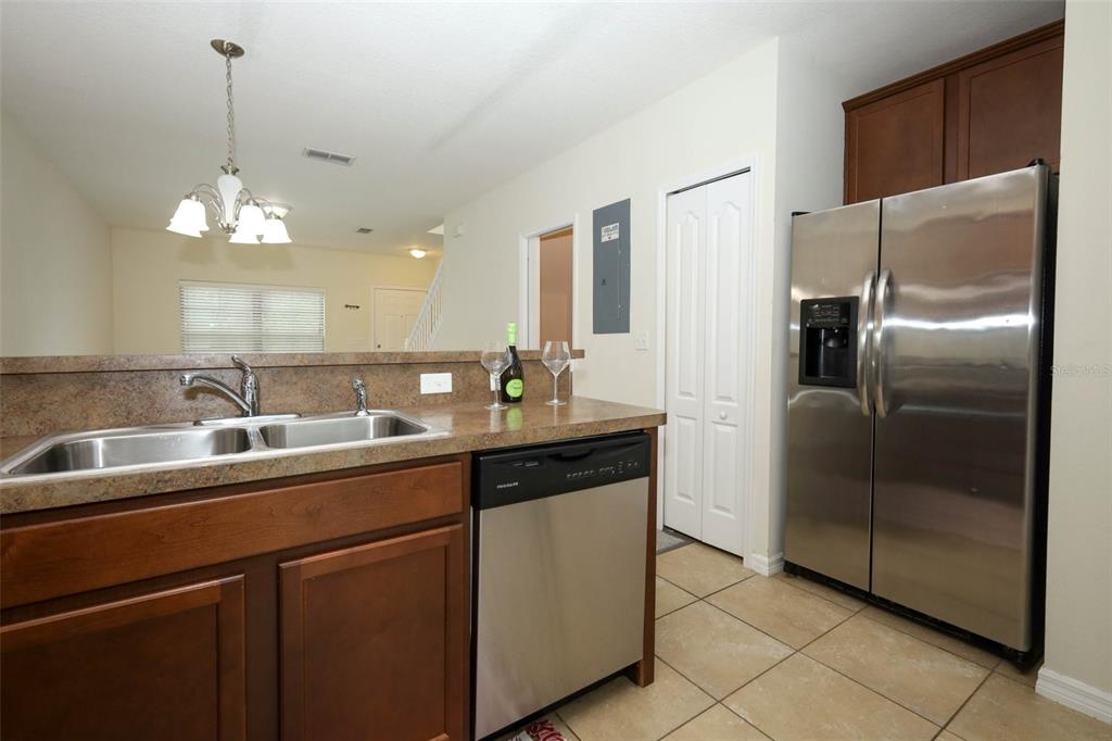 A kitchen features brown cabinets, stainless steel appliances, a double sink, and a breakfast bar — 5221 WINDSOR LAKE CIRCLE, SANFORD, FL
