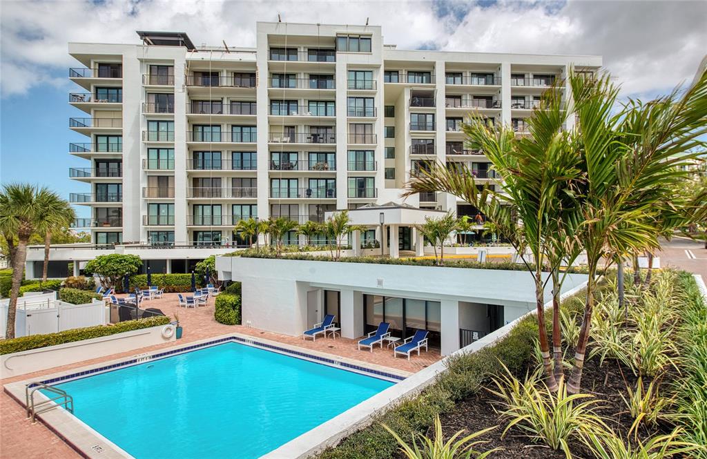 A multi-story white apartment building features a swimming pool and patio area in front — 8 BELLEVIEW BOULEVARD UNIT 702, BELLEAIR, FL