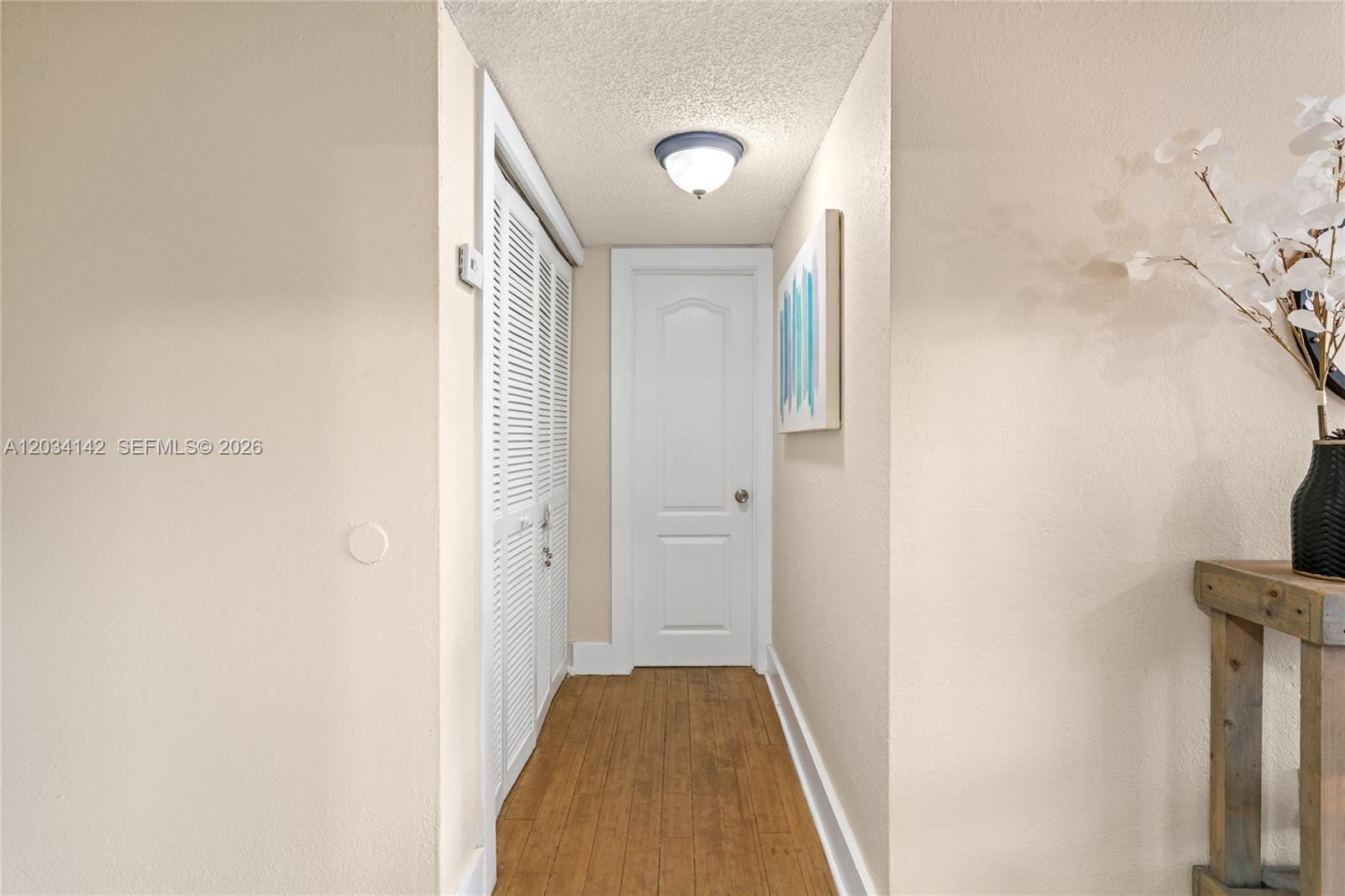 A hallway features wood-look flooring, a white door, louvered closet doors, and a ceiling light — 13120 SW 92nd Ave # 313, Miami FL 33176, MIAMI, FL