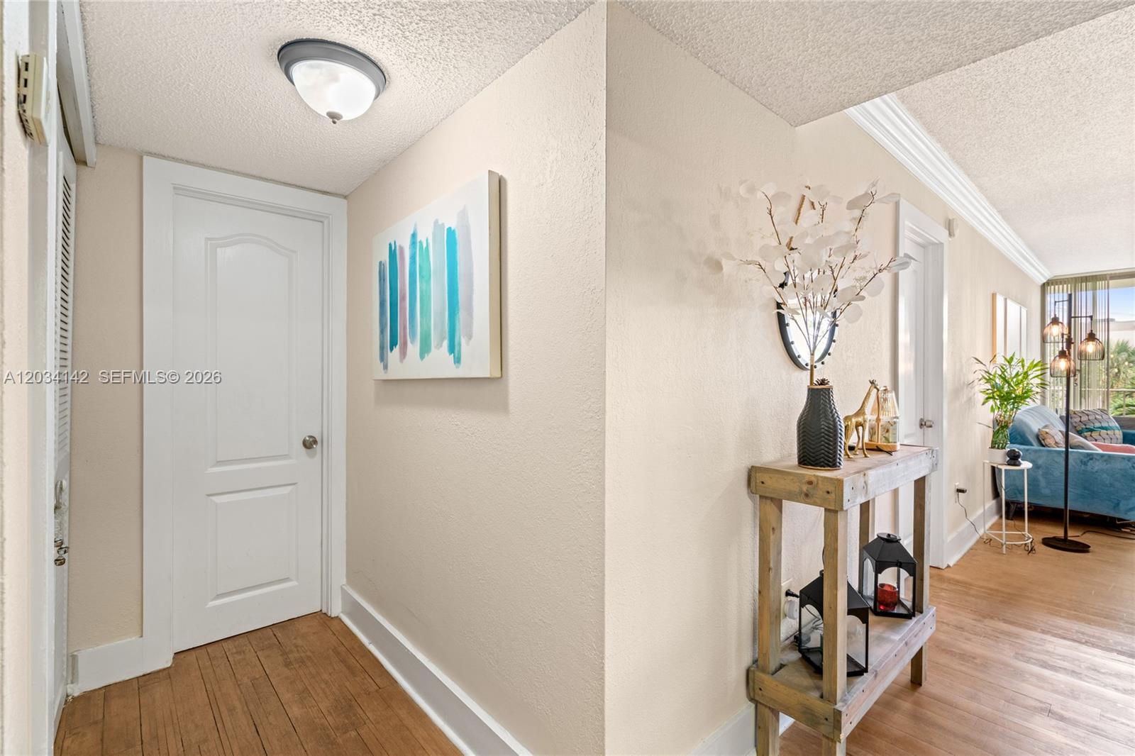 A hallway features light-colored walls, wood flooring, a white door, and a rustic console table — 13120 SW 92nd Ave # 313, Miami FL 33176, MIAMI, FL
