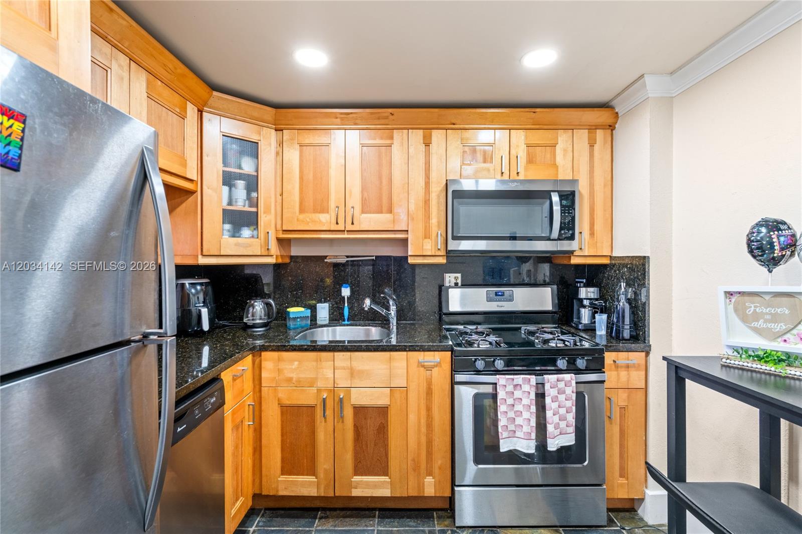A kitchen features light wood cabinets, black granite countertops, and stainless steel appliances — 13120 SW 92nd Ave # 313, Miami FL 33176, MIAMI, FL