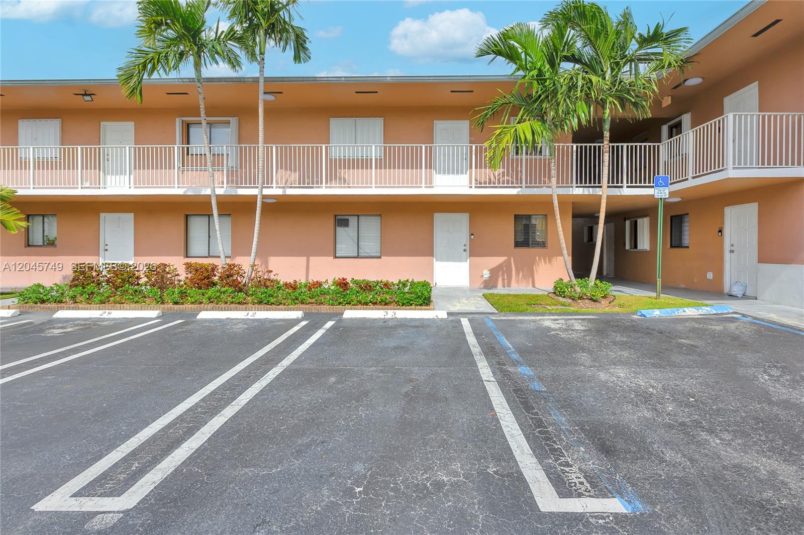 A two-story peach-colored apartment building features white railings, palm trees, and a parking lot — 6041 W 24th Ave # 111, Hialeah FL 33016, HIALEAH, FL