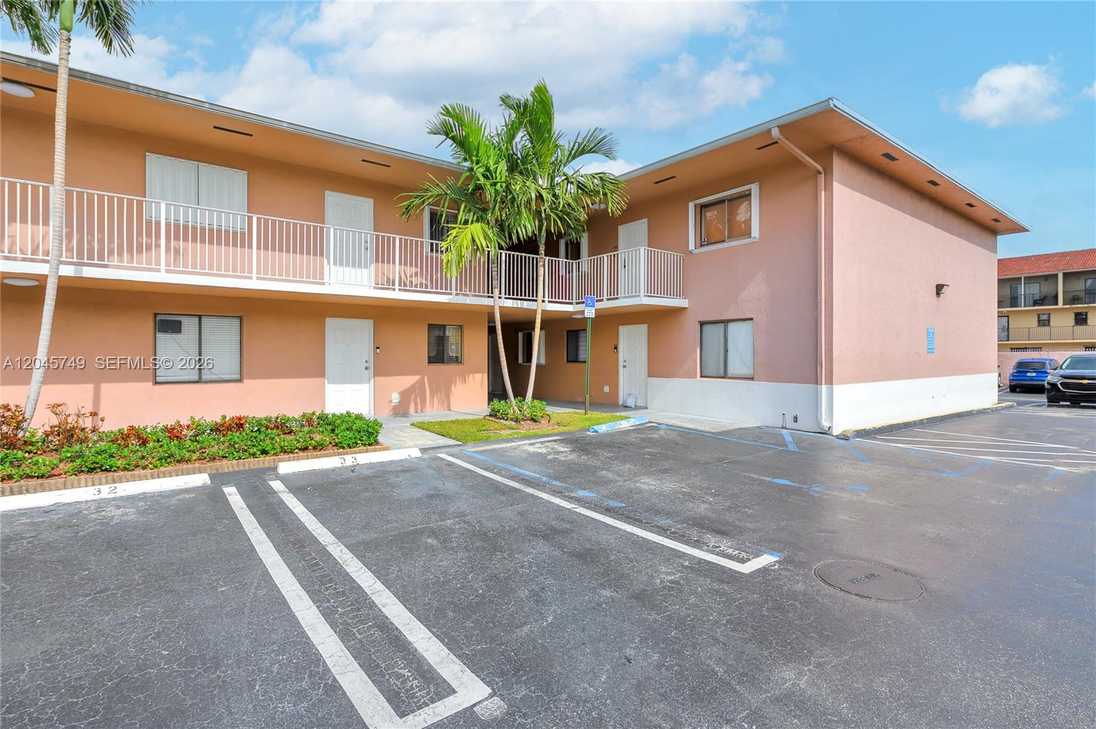 A two-story apartment building exterior features a parking lot, palm trees, and white railings — 6041 W 24th Ave # 111, Hialeah FL 33016, HIALEAH, FL