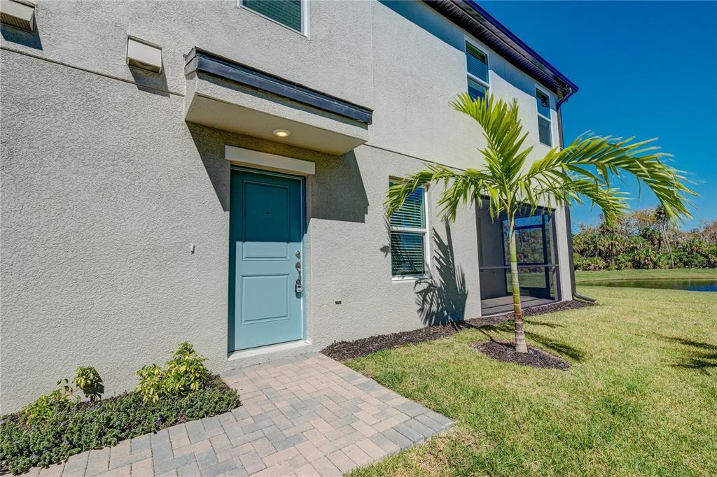 The exterior of a two-story house features a light blue front door and a palm tree — 5512 TRIPOLI DRIVE, PALMETTO, FL