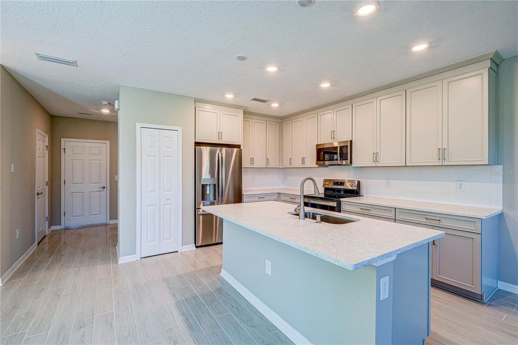 A kitchen features light-colored cabinetry, stainless steel appliances, a central island, and tile flooring — 5512 TRIPOLI DRIVE, PALMETTO, FL