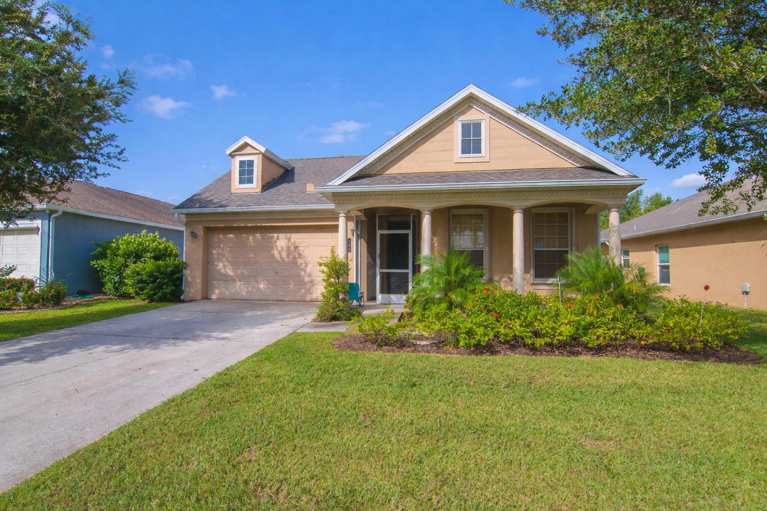 A tan, single-story suburban house with a front porch, garage, and a small dormer window — 504 Sebastian Crossing Boulevard, Sebastian FL 32958, SEBASTIAN, FL