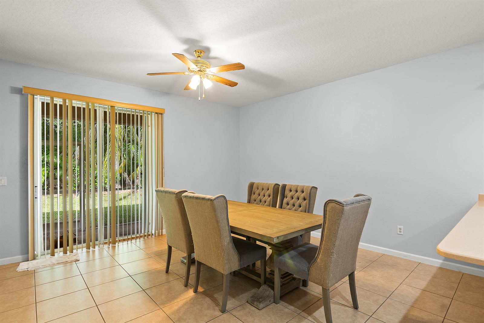 A dining room with a wooden table, upholstered chairs, tile flooring, and a sliding glass door — 504 Sebastian Crossing Boulevard, Sebastian FL 32958, SEBASTIAN, FL