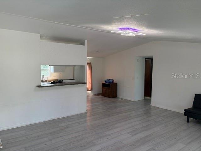 A living room features light wood-look flooring, white walls, and a pass-through kitchen window — 9006 SW 102ND TERRACE, GAINESVILLE, FL