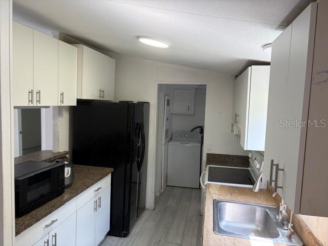 A kitchen features white cabinets, a black refrigerator, a microwave, and a stainless steel sink — 9006 SW 102ND TERRACE, GAINESVILLE, FL