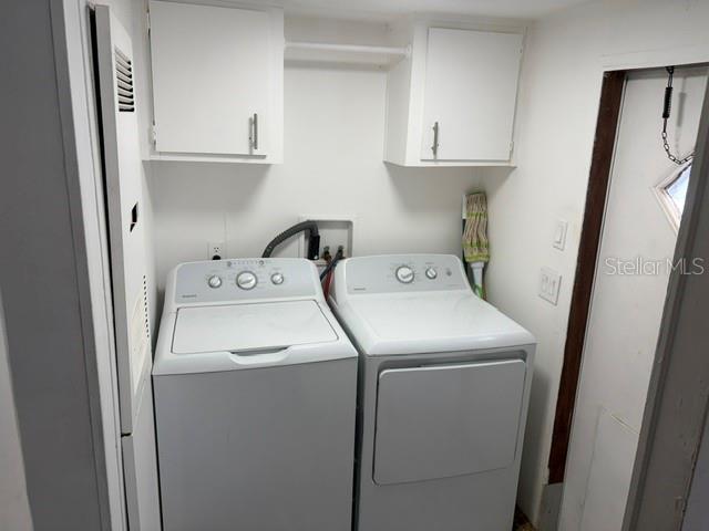 A laundry room features a white washer and dryer, upper cabinets, and a side door — 9006 SW 102ND TERRACE, GAINESVILLE, FL