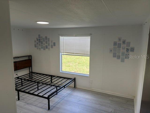 A bedroom features light wood-look flooring, white walls with photo collages, and a metal bed frame — 9006 SW 102ND TERRACE, GAINESVILLE, FL
