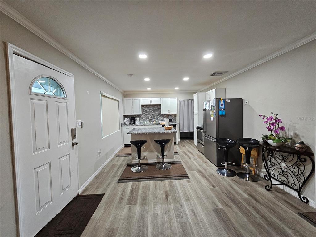A kitchen with white cabinets, a granite-topped island, stainless steel appliances, and wood-look flooring — 2117 IVEY LANE, LAKELAND, FL