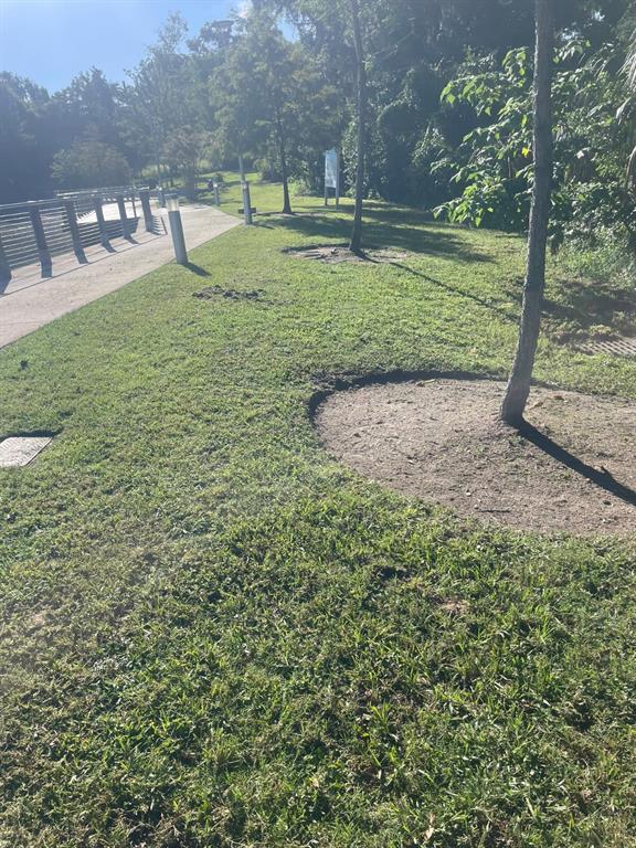 A paved walkway runs alongside a grassy area with several trees and metal light fixtures — 1000 W MONTROSE STREET, CLERMONT, FL