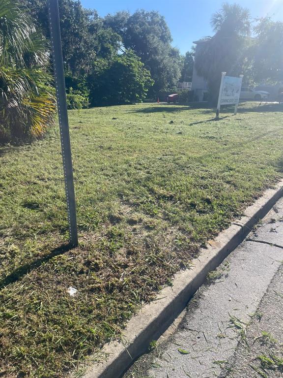 A grassy, vacant lot features a metal sign and a curb along the street — 1000 W MONTROSE STREET, CLERMONT, FL