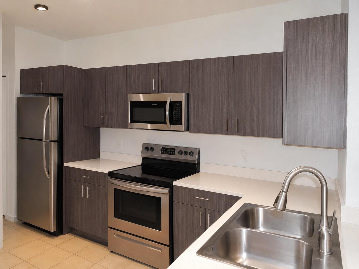 A kitchen features dark wood-grain cabinets, stainless steel appliances, and white countertops — 2488 Cordoba Bend, Weston FL 33327, WESTON, FL