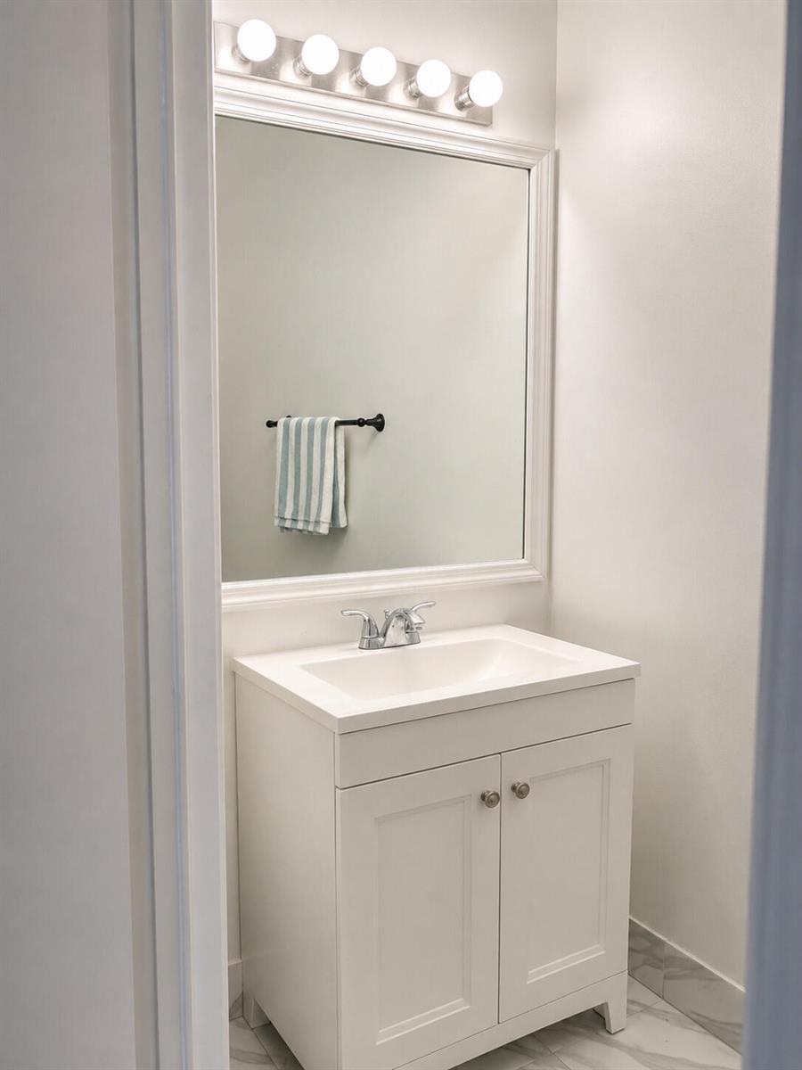 A white bathroom vanity with a mirror, light fixture, and towel bar on a tiled floor — 2488 Cordoba Bend, Weston FL 33327, WESTON, FL