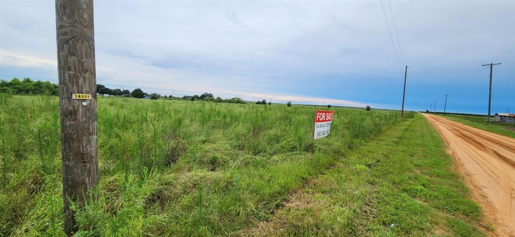 A dirt road runs alongside a large, grassy vacant lot with a for sale sign — WEITA ROAD, BARTOW, FL