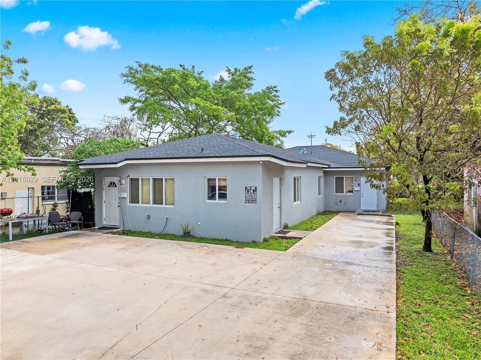 A gray single-story house with a concrete driveway and a fenced yard under a blue sky — 4721 NW 15th Ct # 1, Miami FL 33142, MIAMI, FL