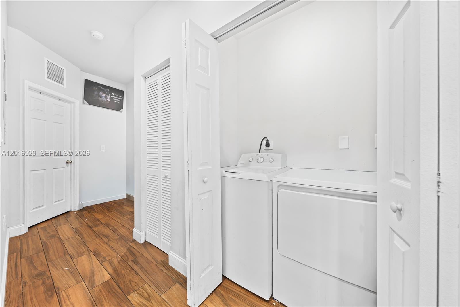A laundry closet with a washer and dryer is situated in a room with wood-look flooring — 4721 NW 15th Ct # 1, Miami FL 33142, MIAMI, FL