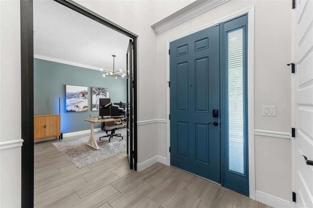 An entryway with light tile flooring, a blue front door, and a glass-paneled office door — 10198 MERRYMEETING BAY DRIVE, WINTER GARDEN, FL