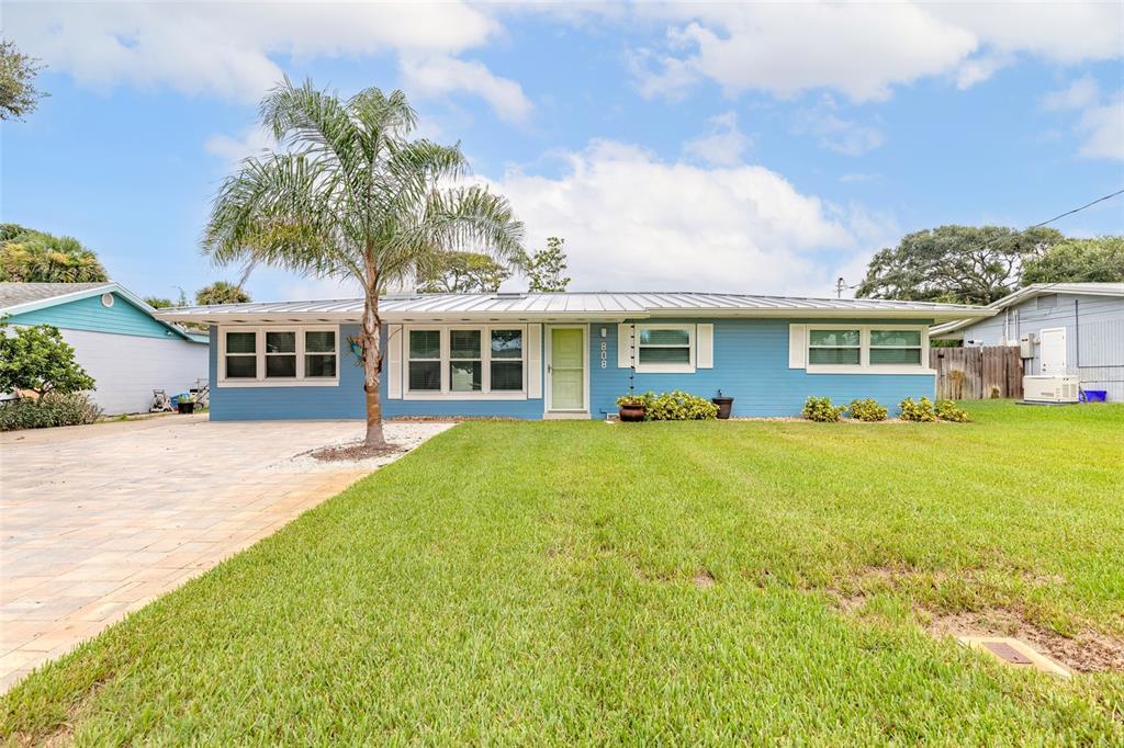 A blue single-story house with a metal roof and a palm tree in the yard — 808 E 16TH AVENUE, NEW SMYRNA BEACH, FL