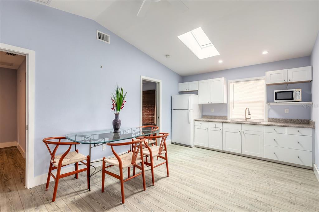 A kitchen and dining area with white cabinets, light wood floors, and a glass table — 808 E 16TH AVENUE, NEW SMYRNA BEACH, FL