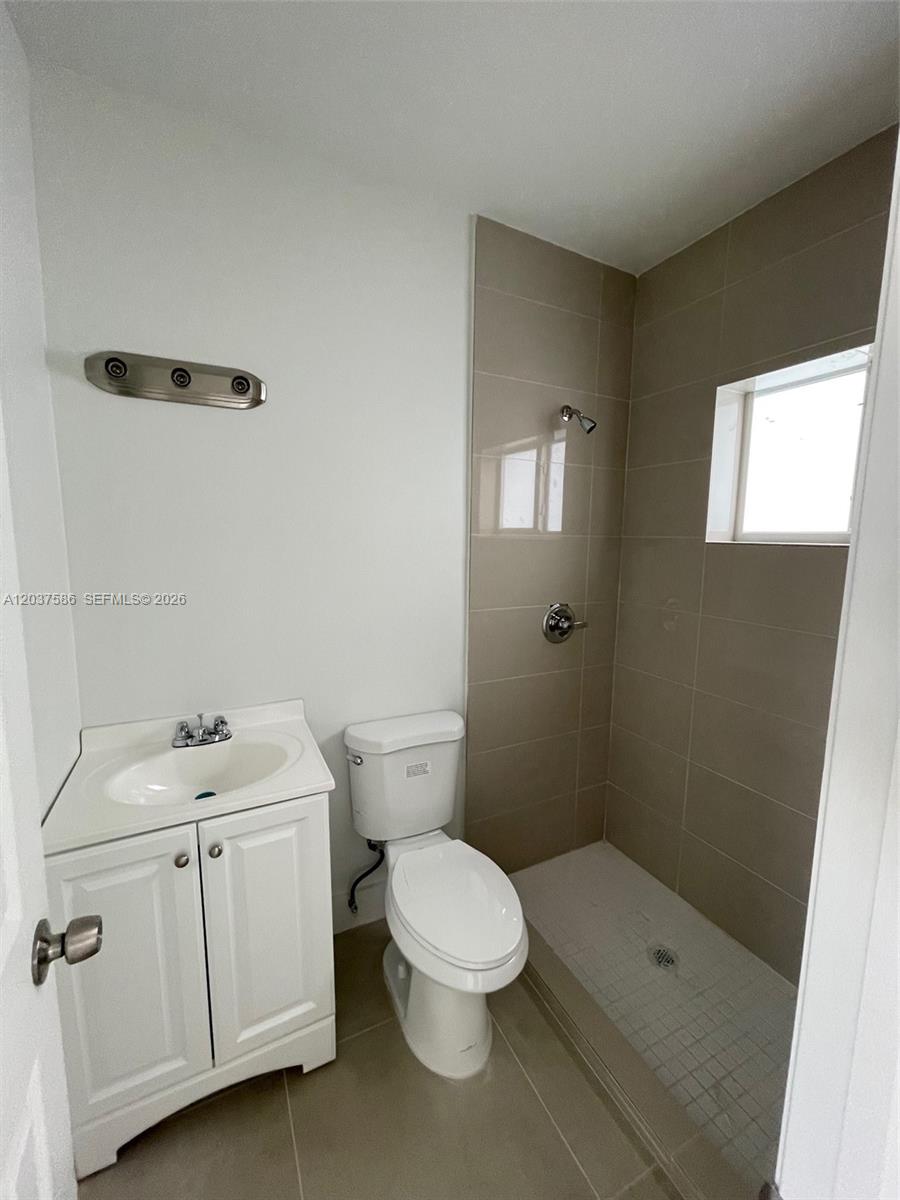 A small bathroom features a white vanity, a toilet, and a tiled walk-in shower — 2196 Ali Baba Ave # 6, Opa-Locka FL 33054, OPA-LOCKA, FL